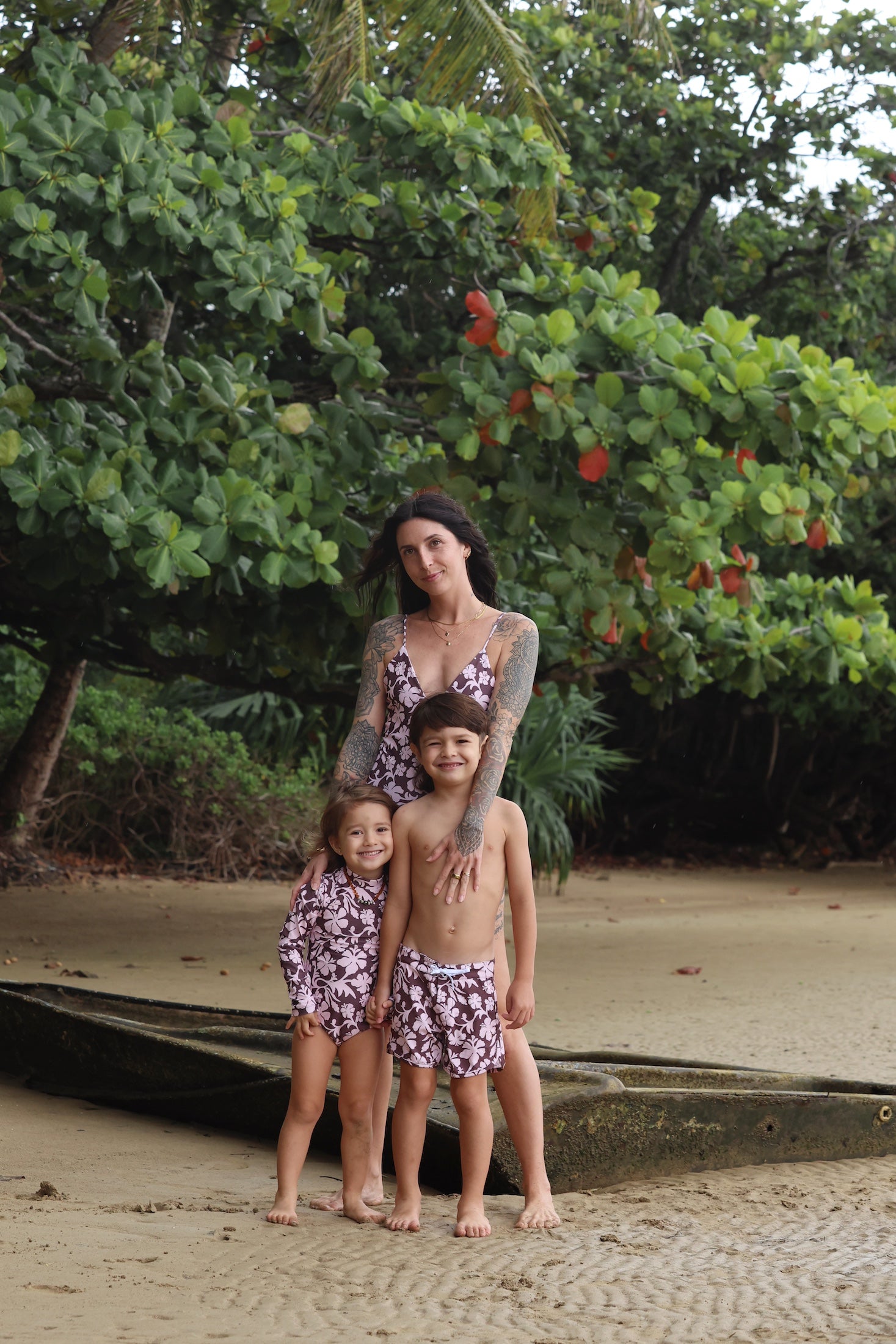 little boy wearing board shorts in blush and brown hibiscus print.