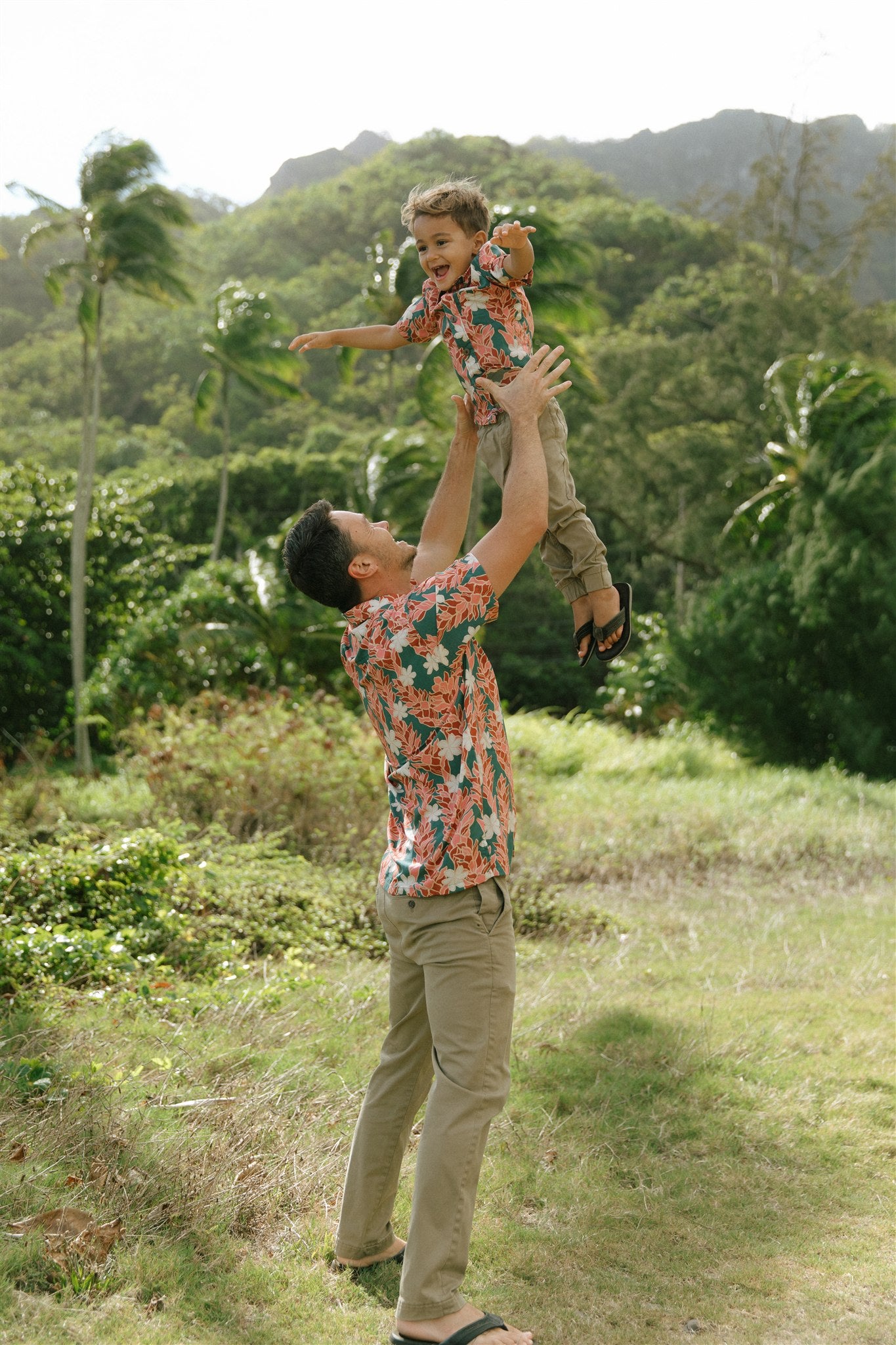 little boy wearing an aloha button up shirt with red ginger and tiare print
