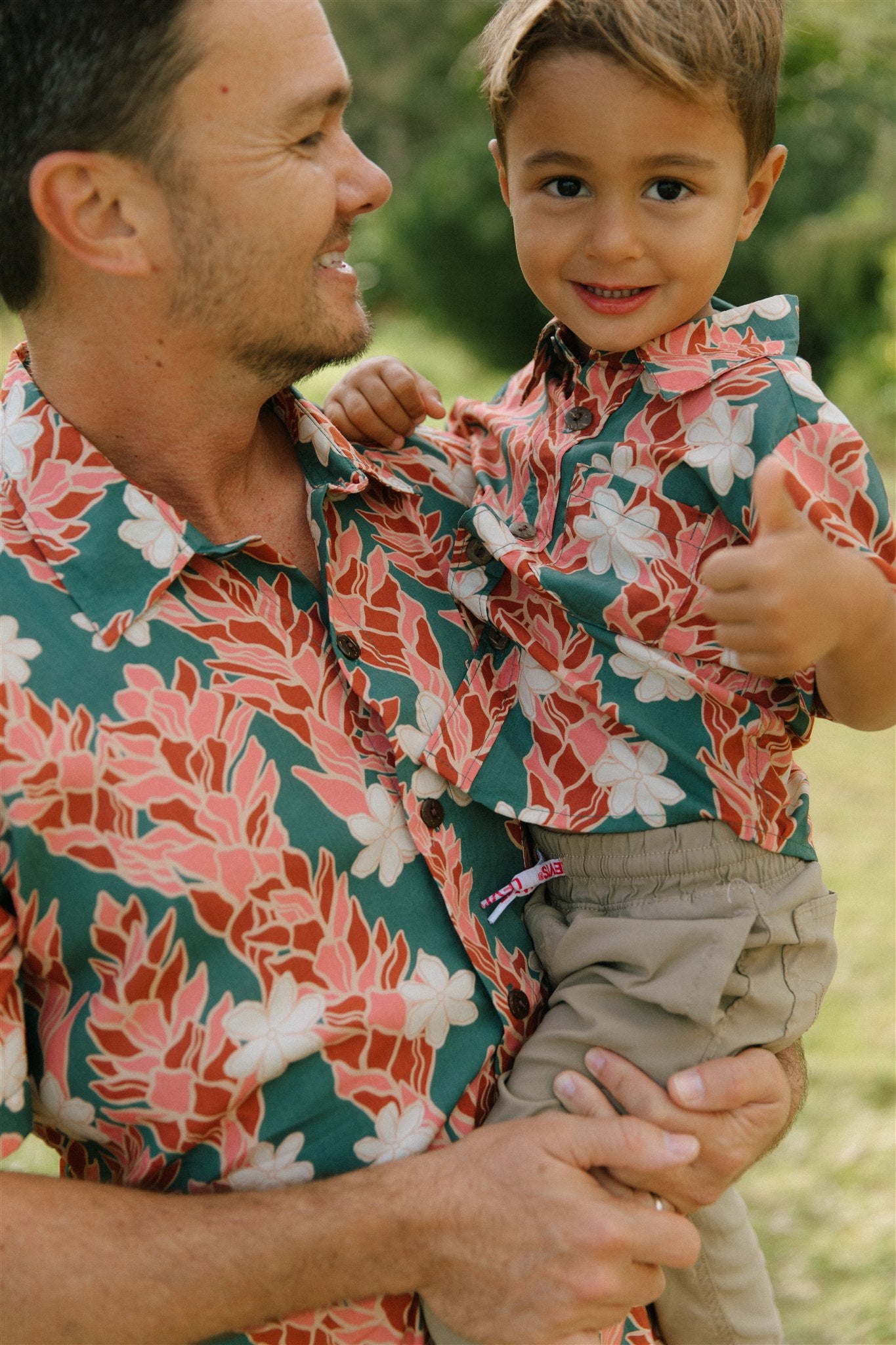 little boy wearing an aloha button up shirt with red ginger and tiare print