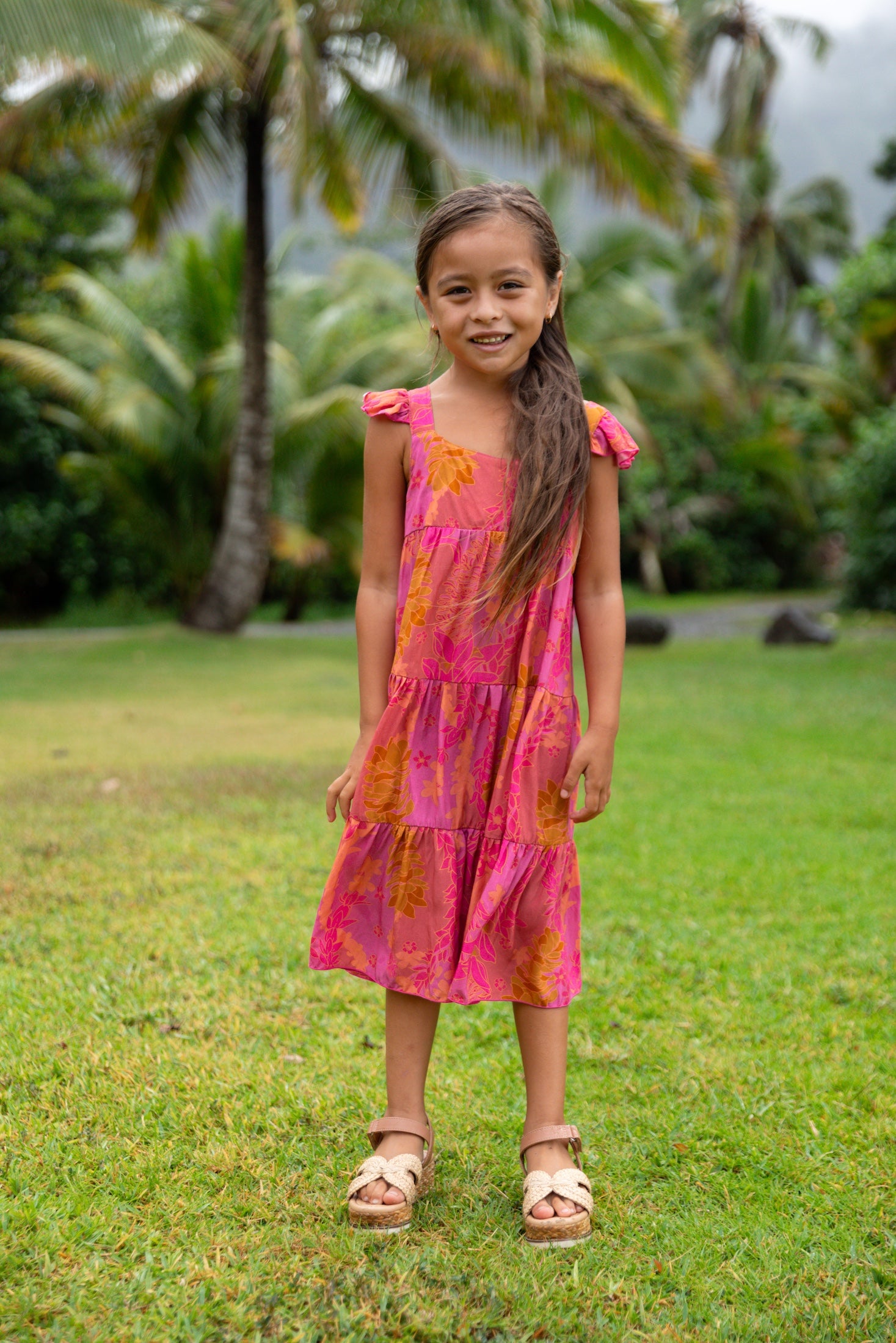 little girl wearing a long pink tiered dress with ruffle straps