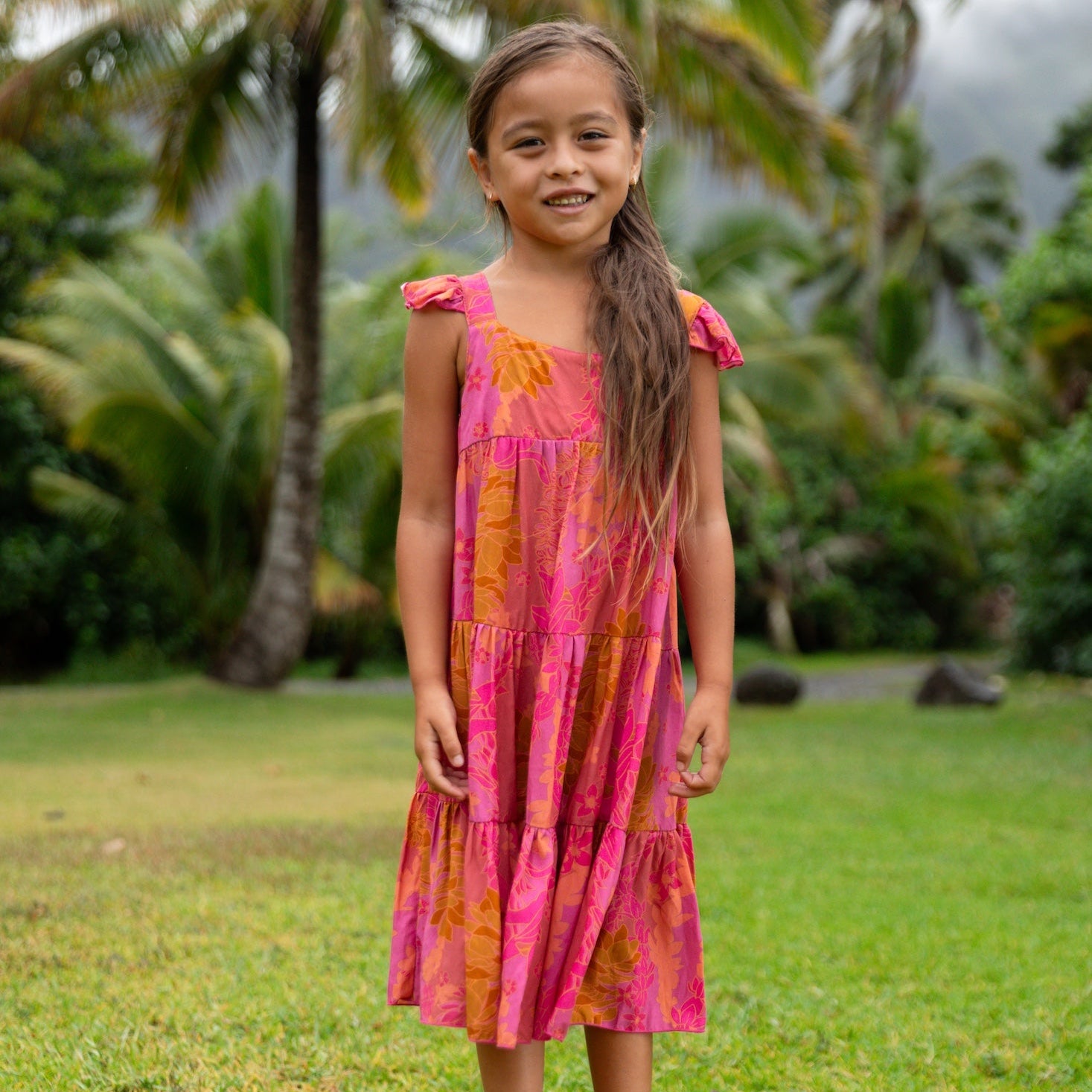 little girl wearing a long pink tiered dress with ruffle straps