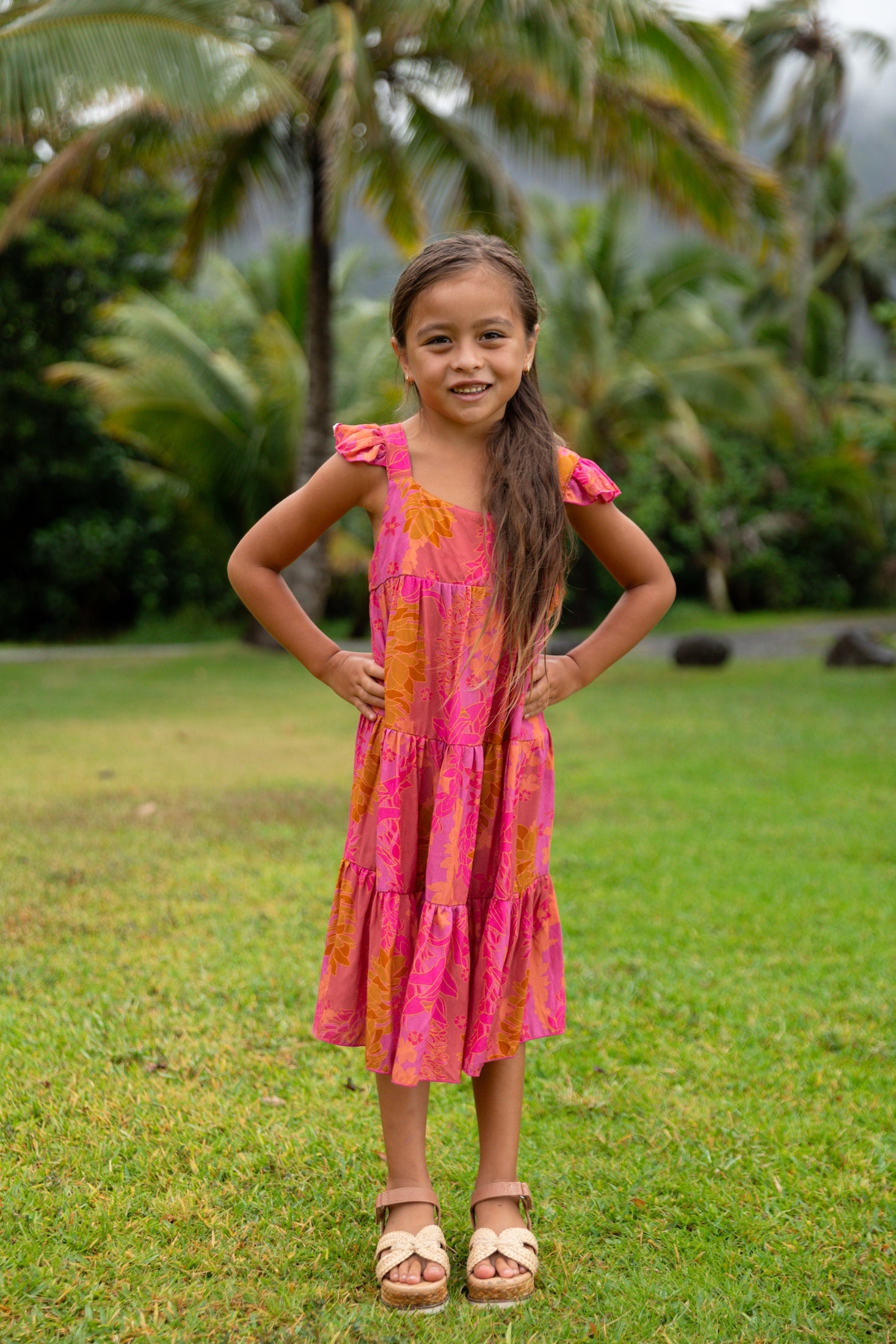 little girl wearing a long pink tiered dress with ruffle straps