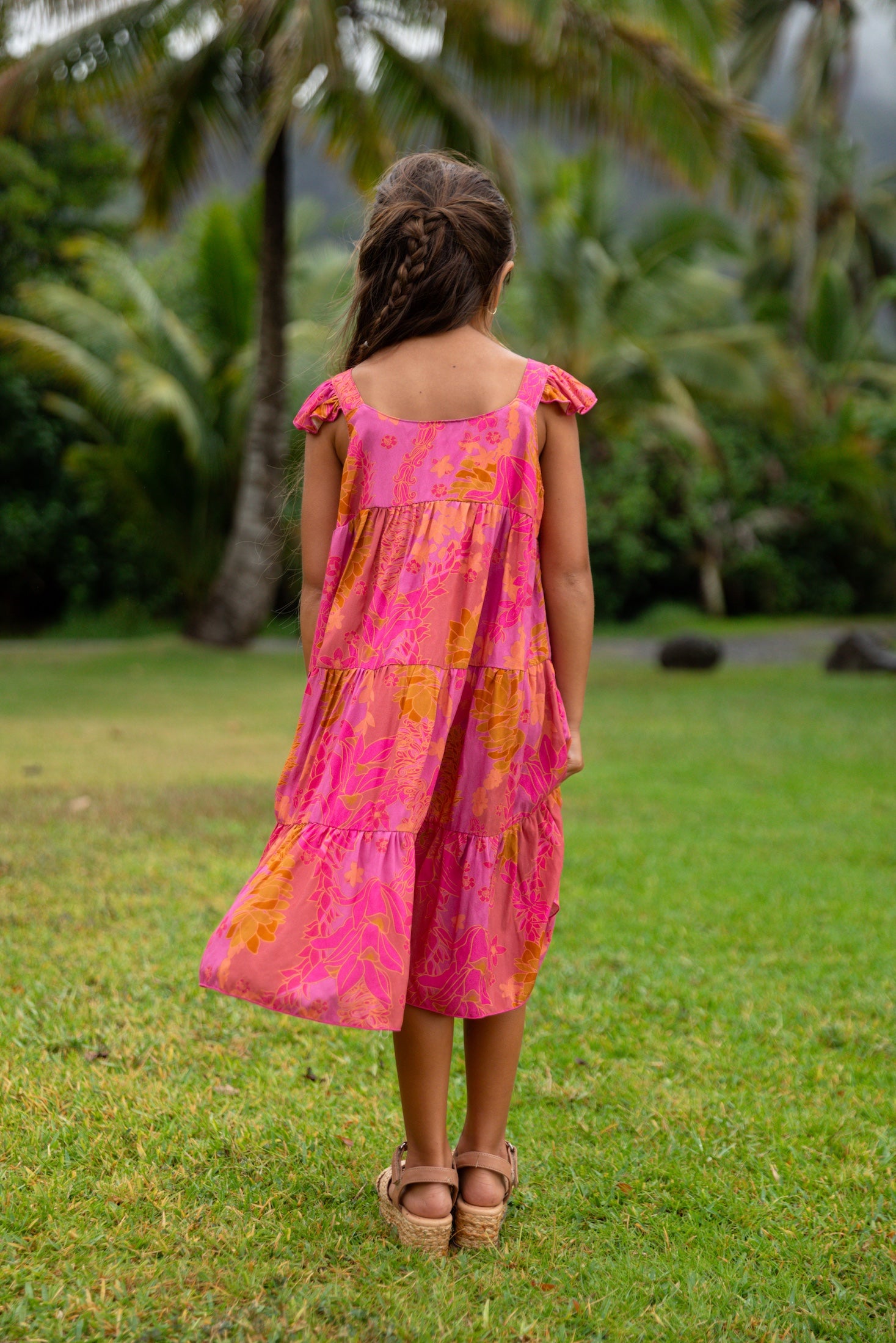 little girl wearing a long pink tiered dress with ruffle straps