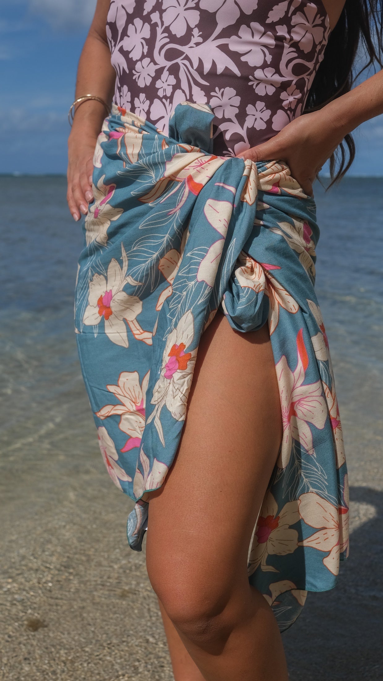 woman wearing a teal pareo with cream colored orchid pattern