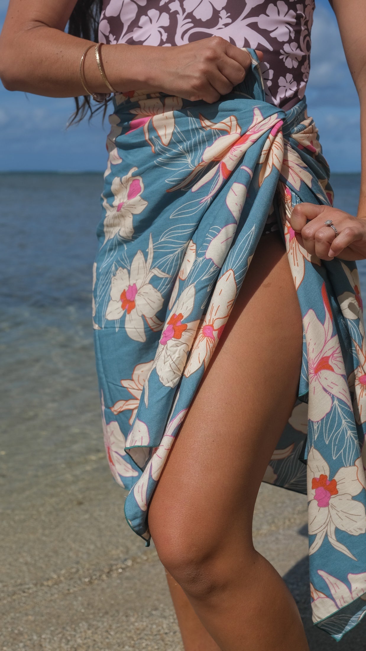 woman wearing a teal pareo with cream colored orchid pattern