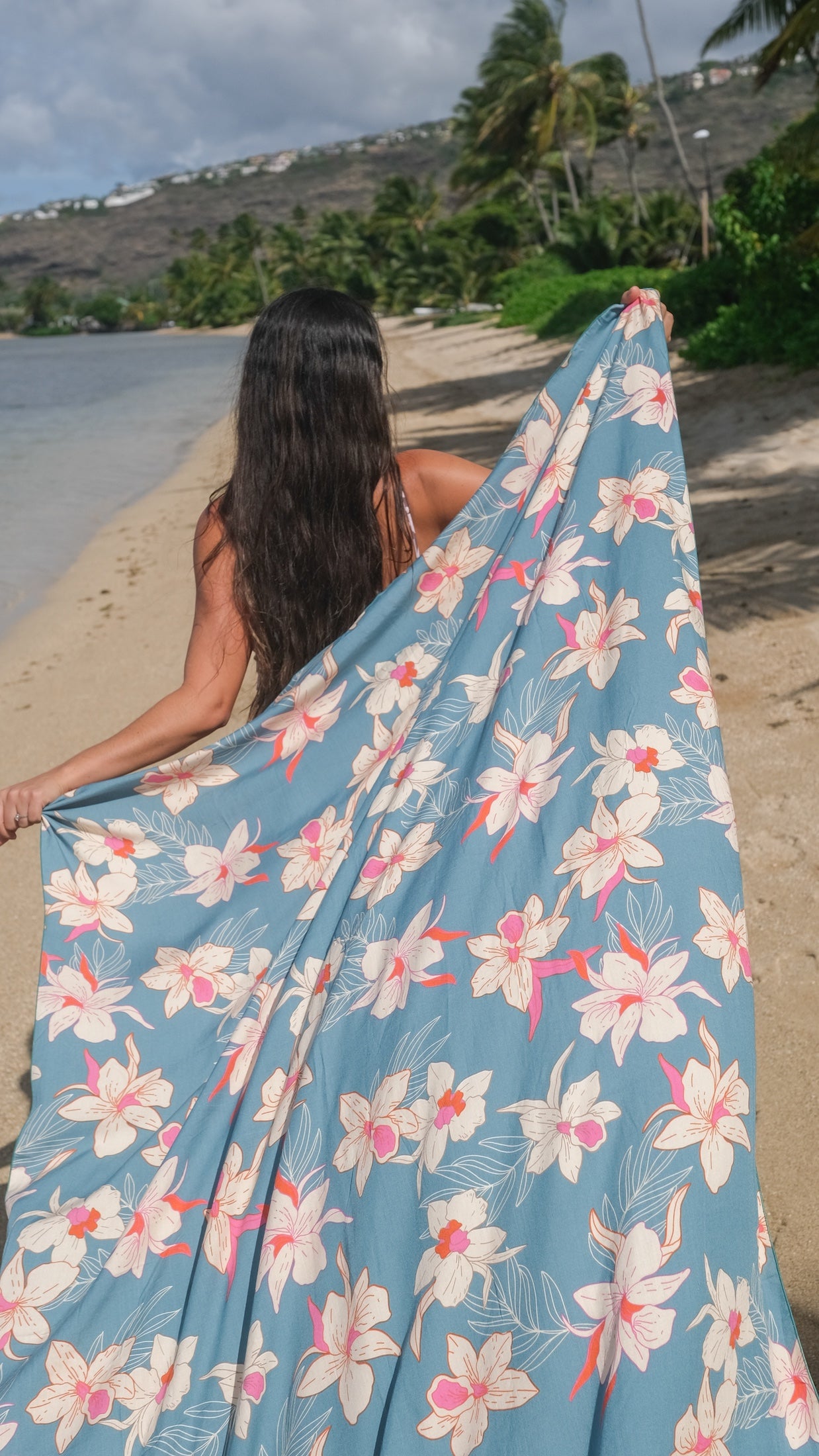 woman wearing a teal pareo with cream colored orchid pattern