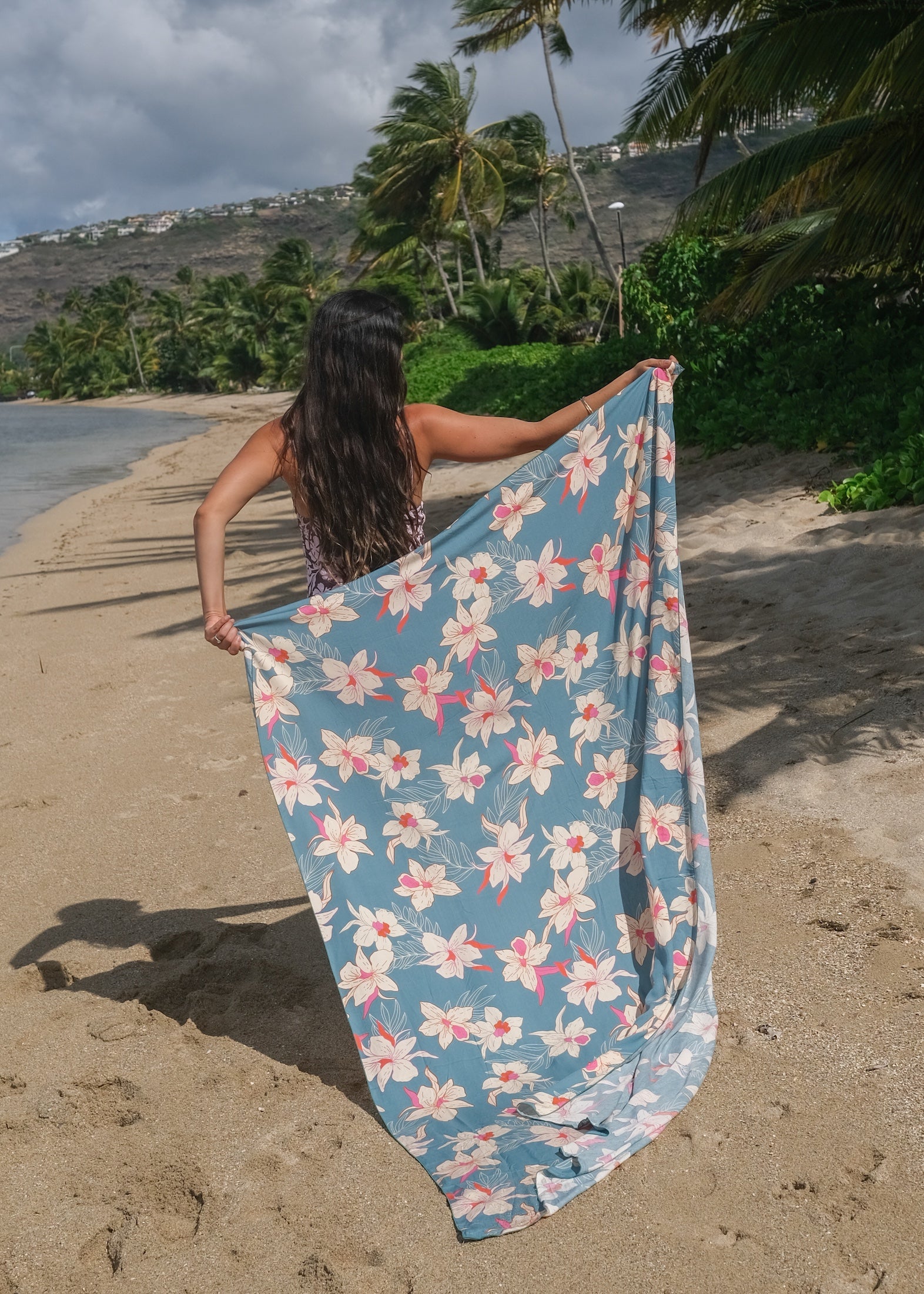 woman wearing a teal pareo with cream colored orchid pattern