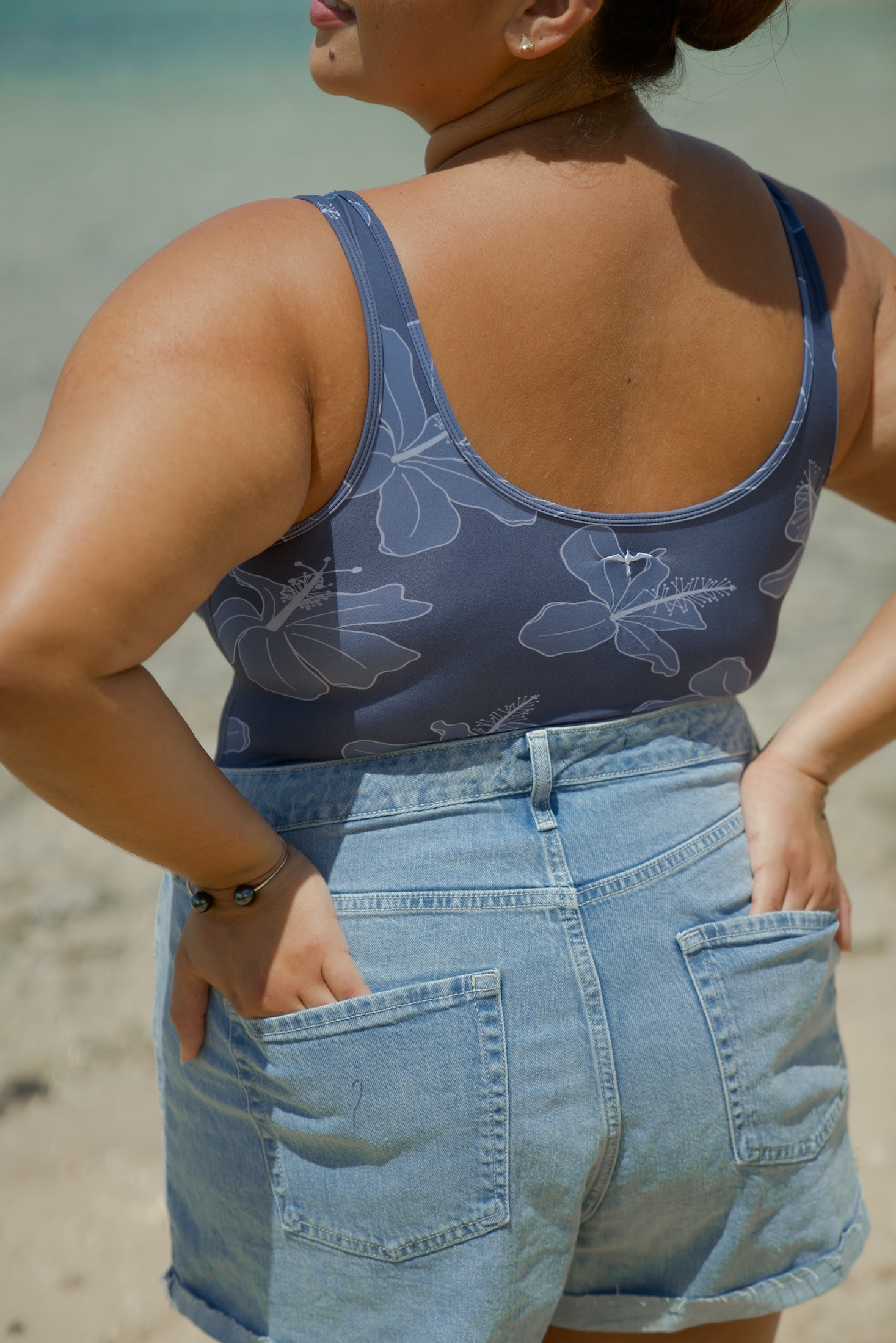 woman wearing a bodysuit with blue hibiscus pattern