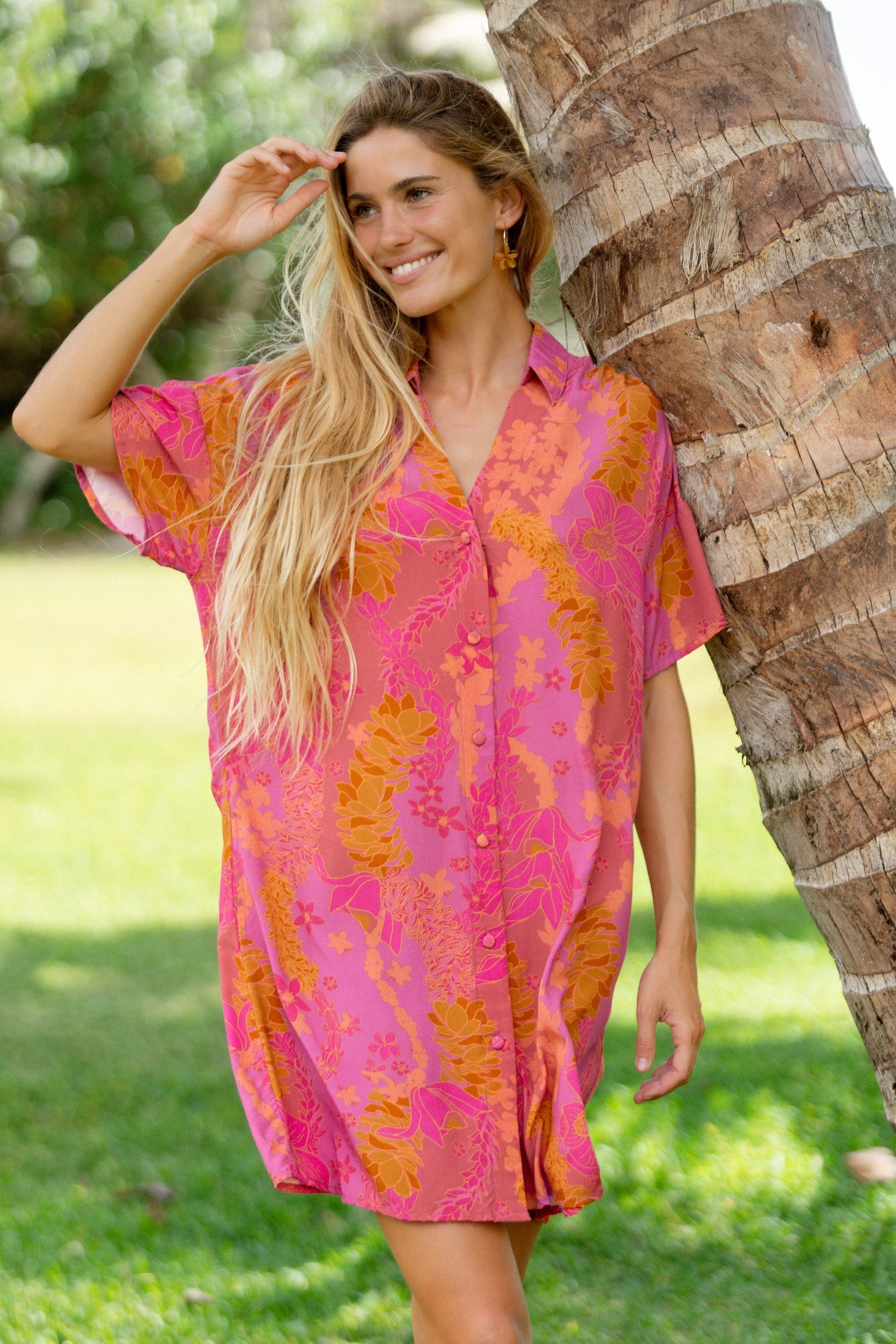 woman wearing a pink v neck button up mini dress with lei print