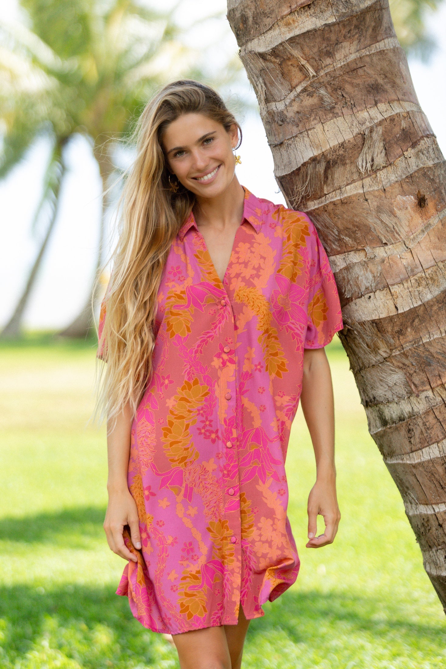 woman wearing a pink v neck button up mini dress with lei print