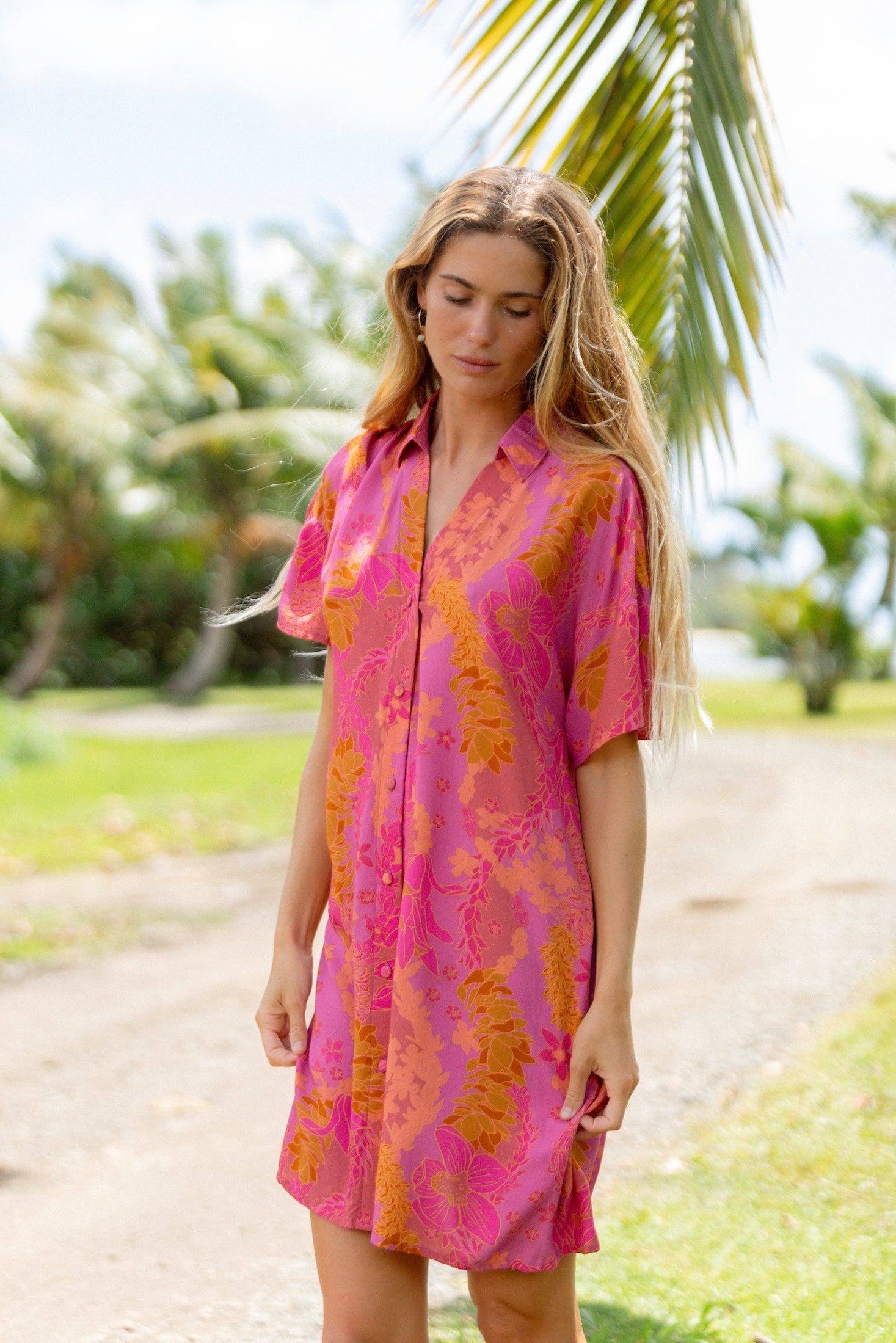 woman wearing a pink v neck button up mini dress with lei print