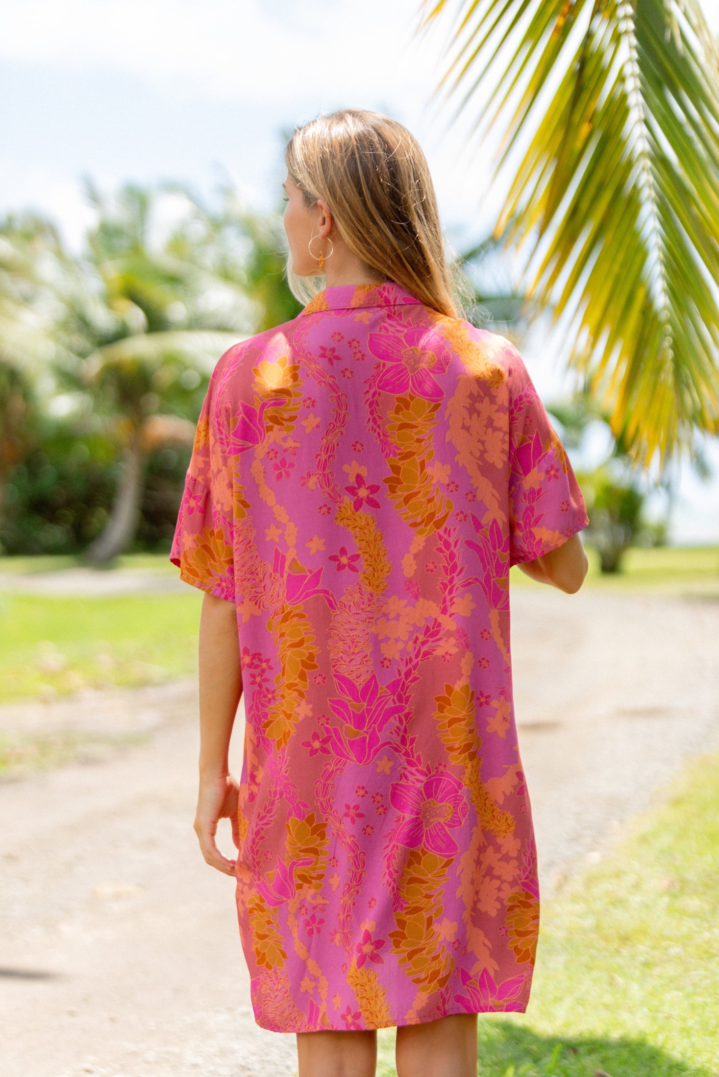 woman wearing a pink v neck button up mini dress with lei print