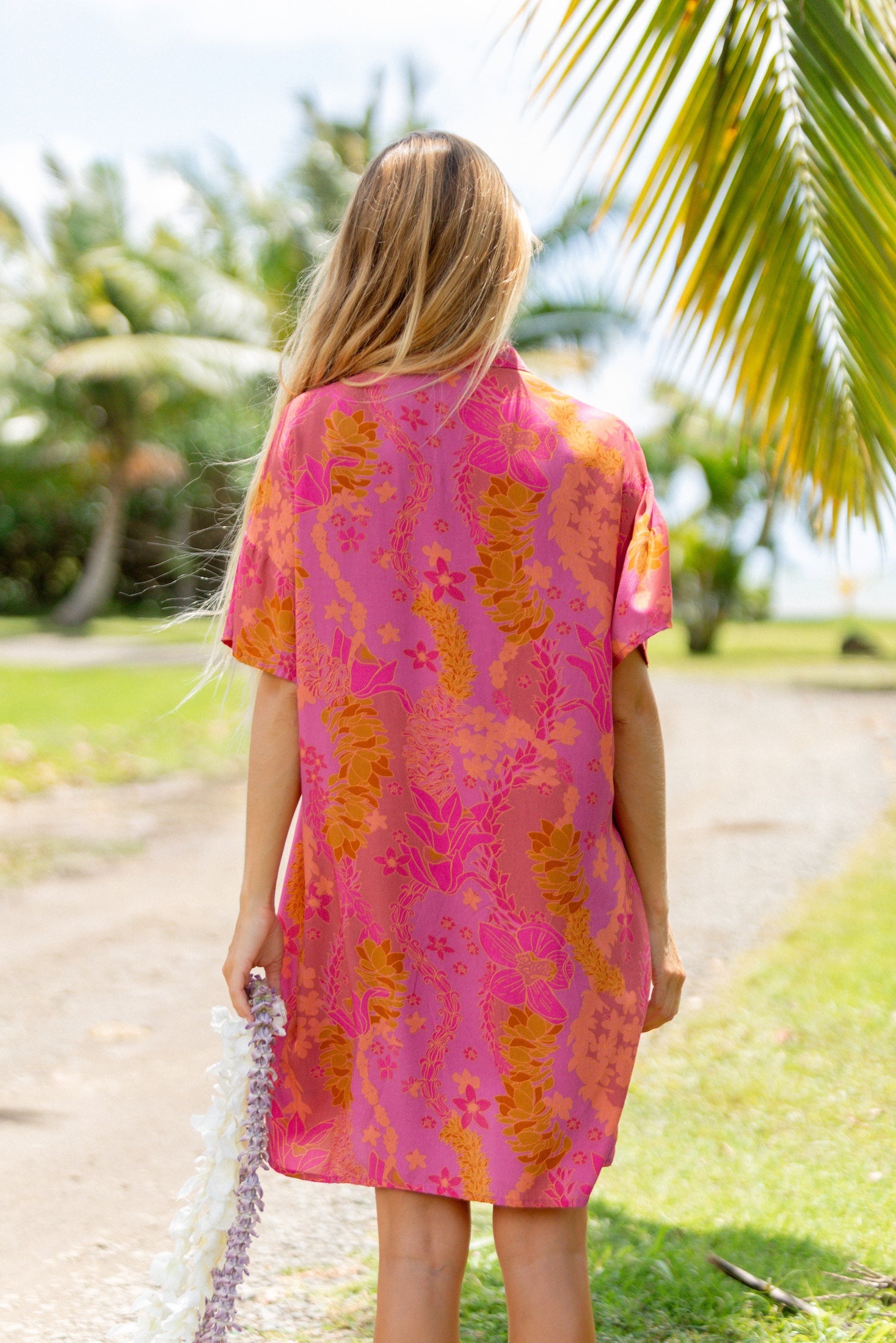 woman wearing a pink v neck button up mini dress with lei print