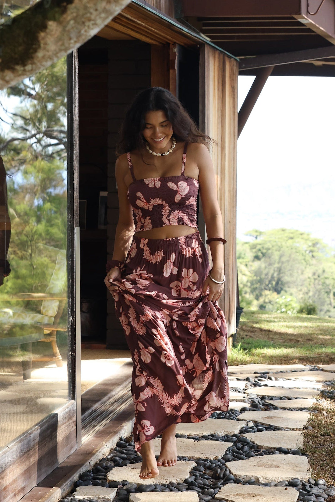 woman wearing brown maxi skirt with light pink lei awapuhi print