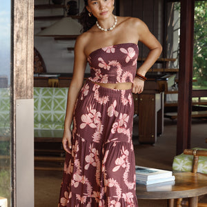 woman wearing brown maxi skirt with light pink lei awapuhi print