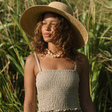 Woman wearing smocked beige linen tube top with spaghetti straps.