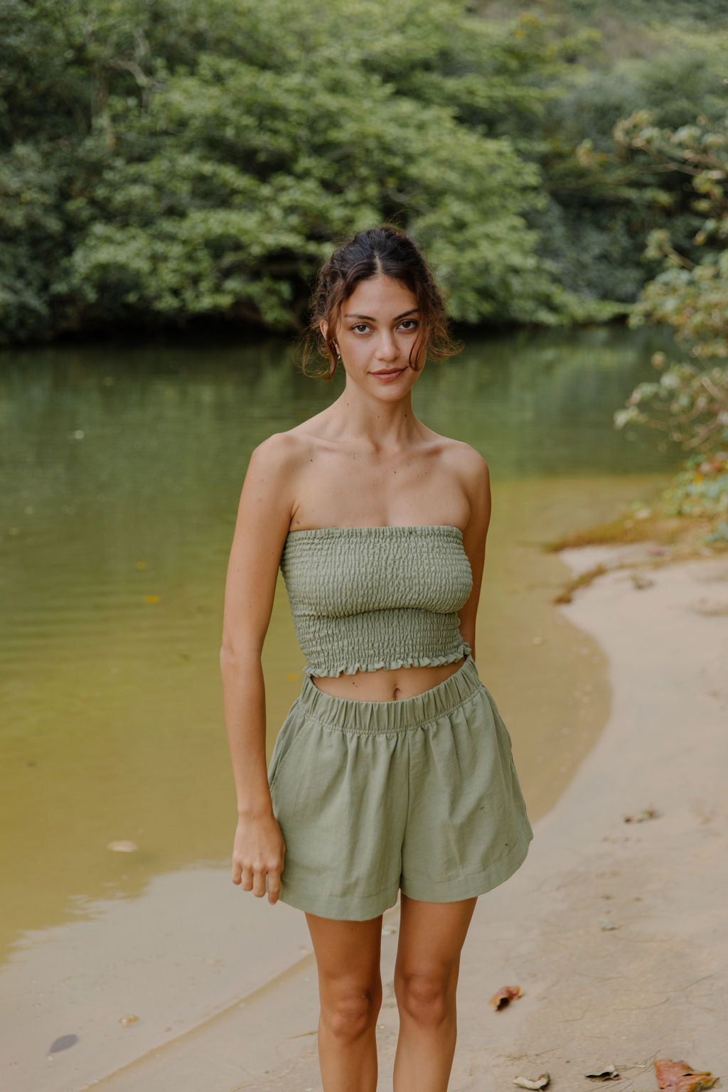 Woman wearing smocked tube top and short in medium green linen.