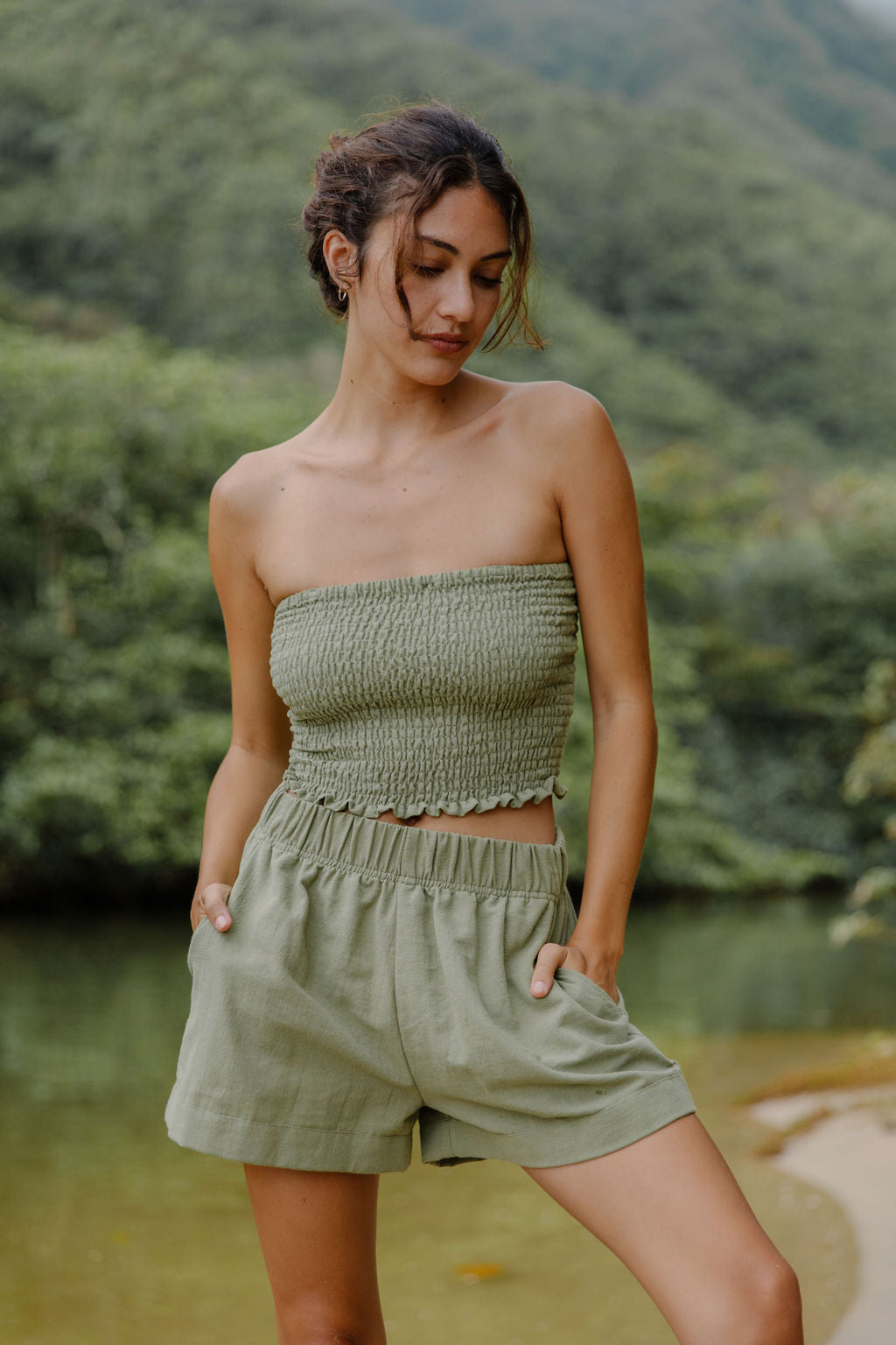 Woman wearing smocked tube top and short in medium green linen.