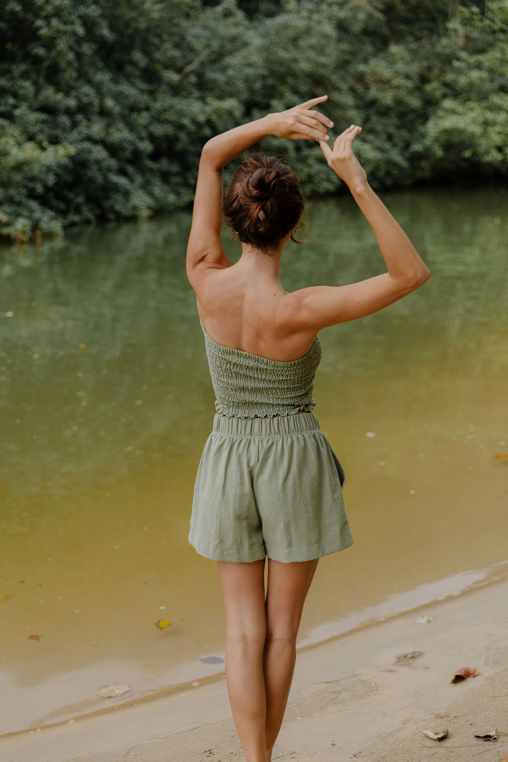 Woman wearing smocked tube top and short in medium green linen.