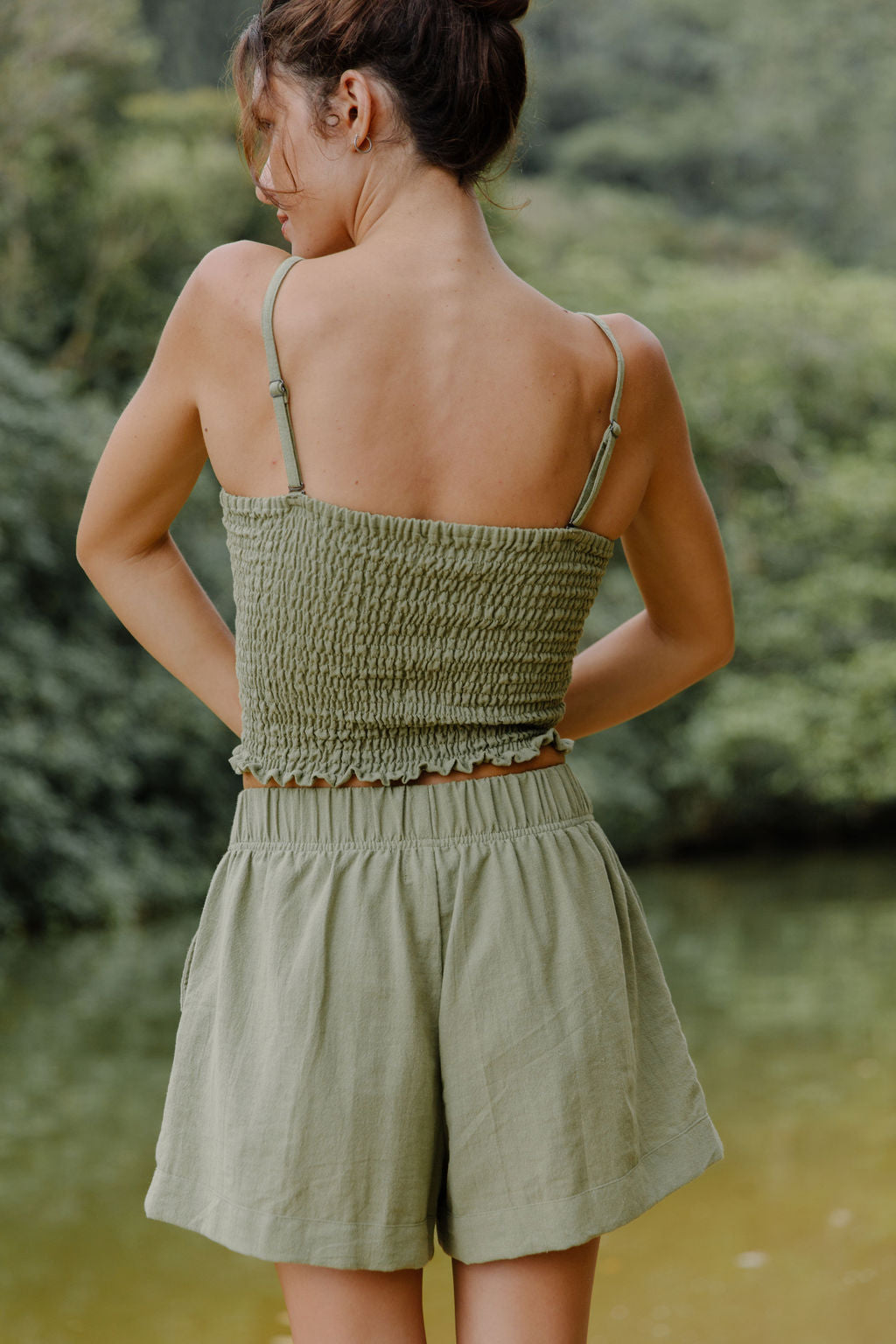 Woman wearing smocked tube top with spaghetti straps and short in medium green linen.