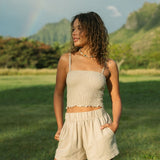 Woman wearing smocked beige linen tube top with spaghetti straps and short.