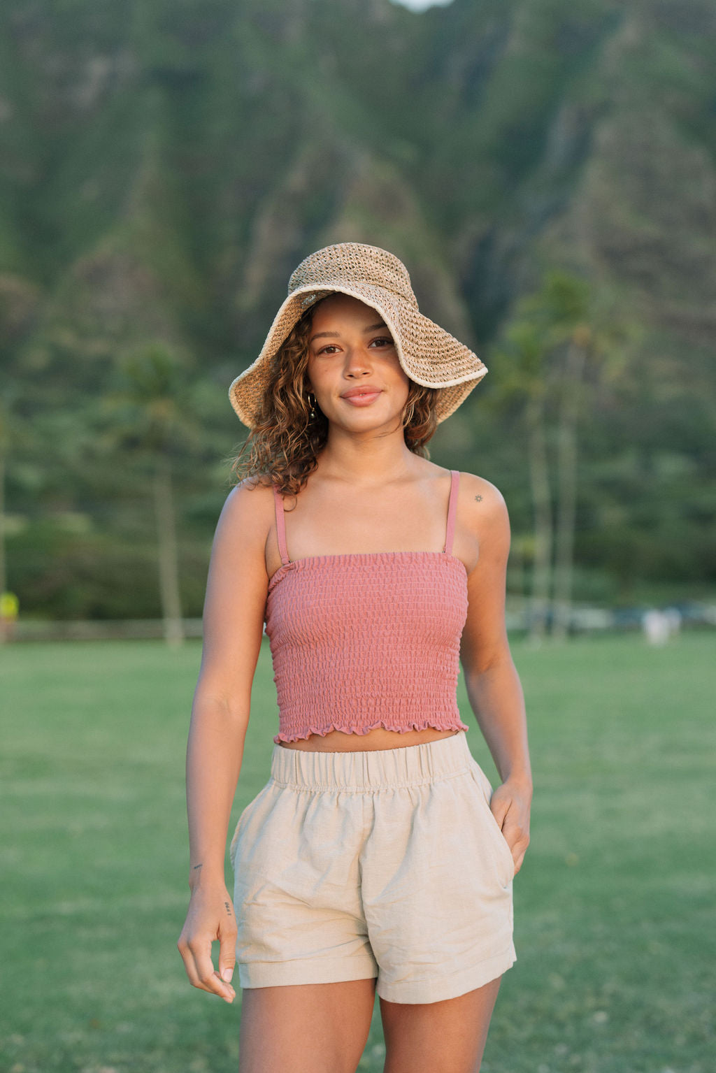 Woman wearing rose linen smocked tube top with spaghetti straps.