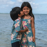 little girl wearing a teal flowy dress with cream colored orchid pattern