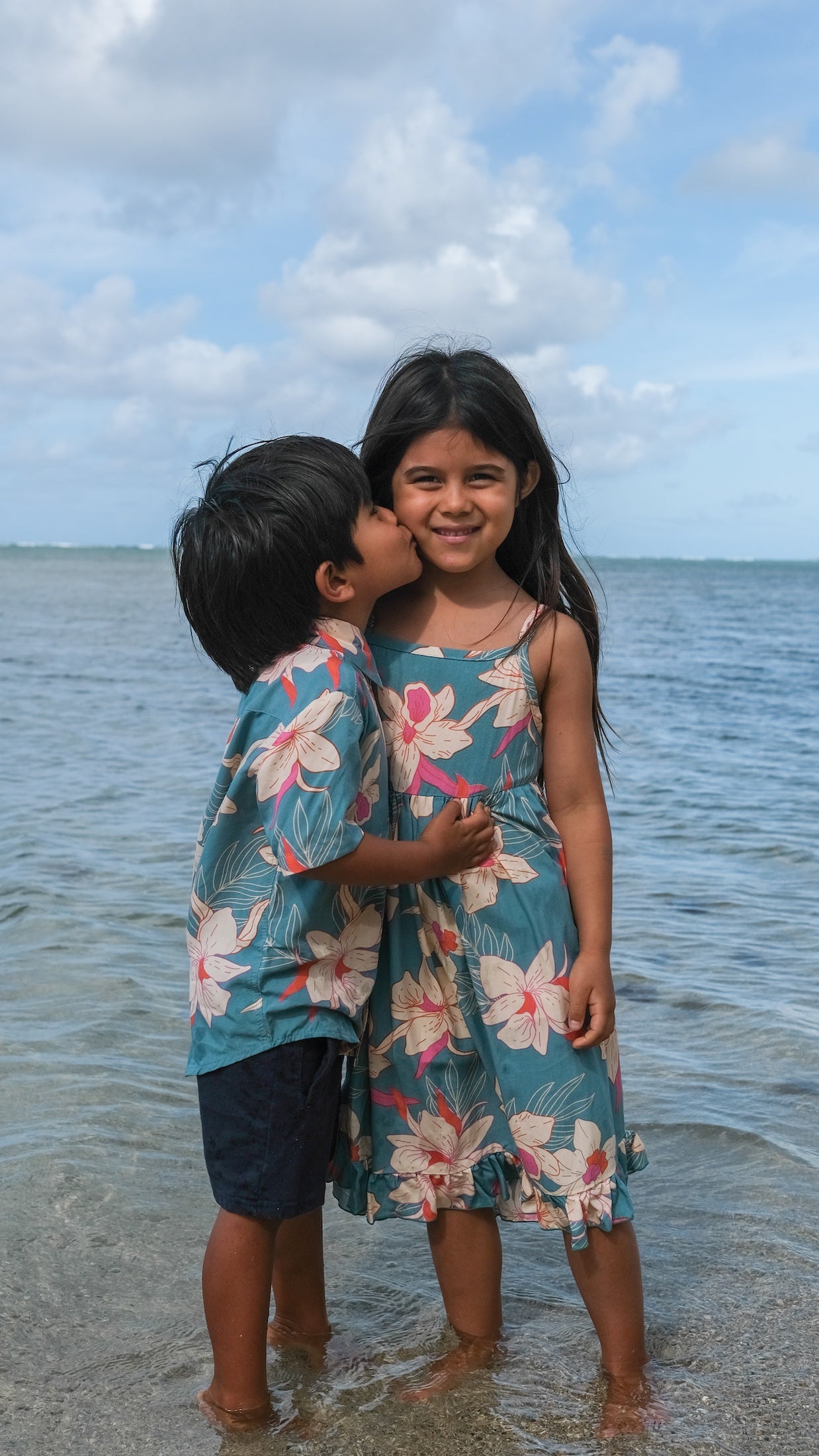 little girl wearing a teal flowy dress with cream colored orchid pattern
