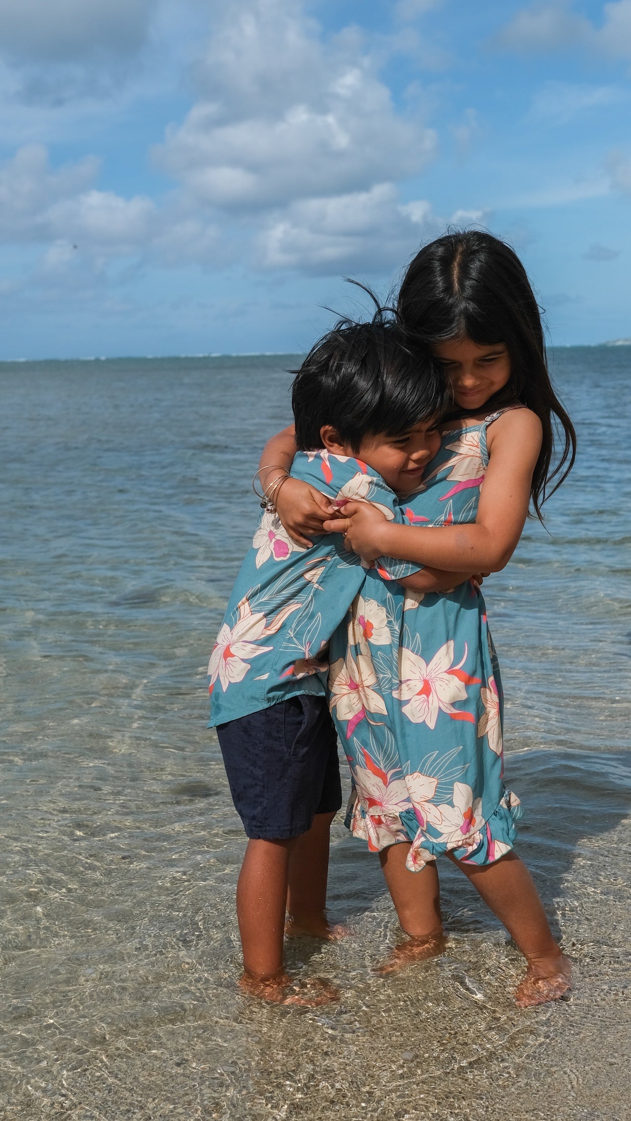 little boy wearing a teal aloha shirt with cream colored orchid blossom pattern