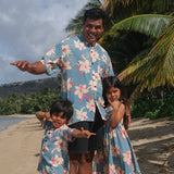 little girl wearing a teal flowy dress with cream colored orchid pattern