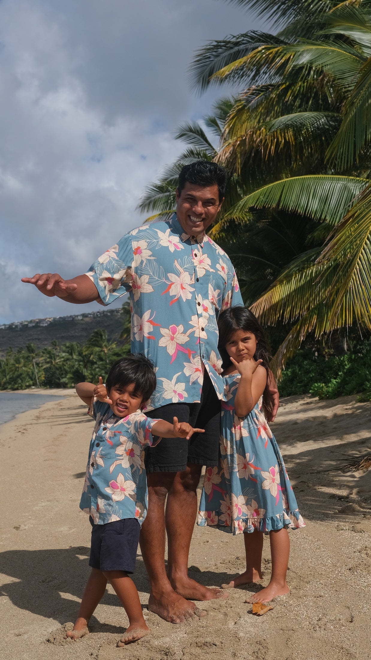 little girl wearing a teal flowy dress with cream colored orchid pattern
