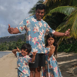 man wearing a teal aloha button up shirt with cream colored orchid pattern