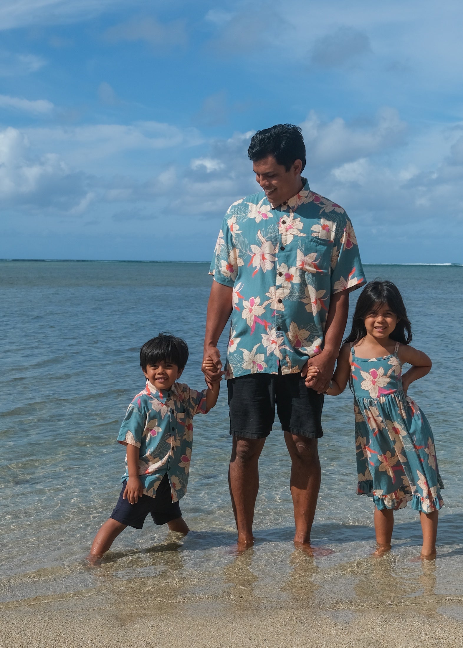 man wearing a teal aloha button up shirt with cream colored orchid pattern