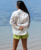 The YIREH A La Mode Button-Up in Cloud is a linen, slightly oversized, long-sleeve button-up featuring mother-of-pearl shell buttons. - back view w/ Parakeet Millie Short