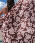 woman with brown hair wearing a pareo with blush pink and brown hibiscus print 
