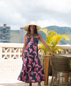 Woman wearing a dark blue sundress featuring pink ginger flowers and lei.