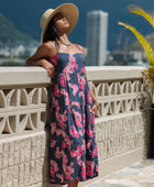 Woman wearing a dark blue sundress featuring pink ginger flowers and lei.