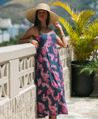 Woman wearing a dark blue sundress featuring pink ginger flowers and lei.