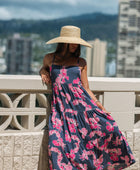 Woman wearing a dark blue sundress featuring pink ginger flowers and lei.