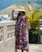 Woman wearing a dark blue sundress featuring pink ginger flowers and lei.