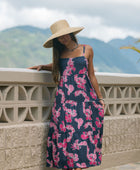 Woman wearing a dark blue sundress featuring pink ginger flowers and lei.