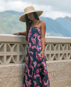 Woman wearing a dark blue sundress featuring pink ginger flowers and lei.