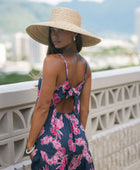 Woman wearing a dark blue sundress featuring pink ginger flowers and lei.