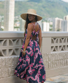 Woman wearing a dark blue sundress featuring pink ginger flowers and lei.