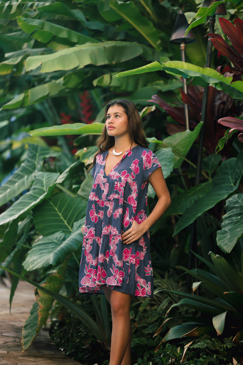 Woman wearing dress in navy with pink ginger and lei print.