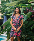 Woman wearing dress in navy with pink ginger and lei print.