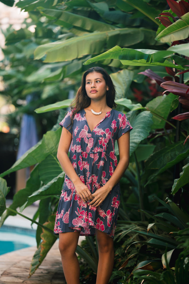 Woman wearing dress in navy with pink ginger and lei print.