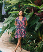 Woman wearing dress in navy with pink ginger and lei print.