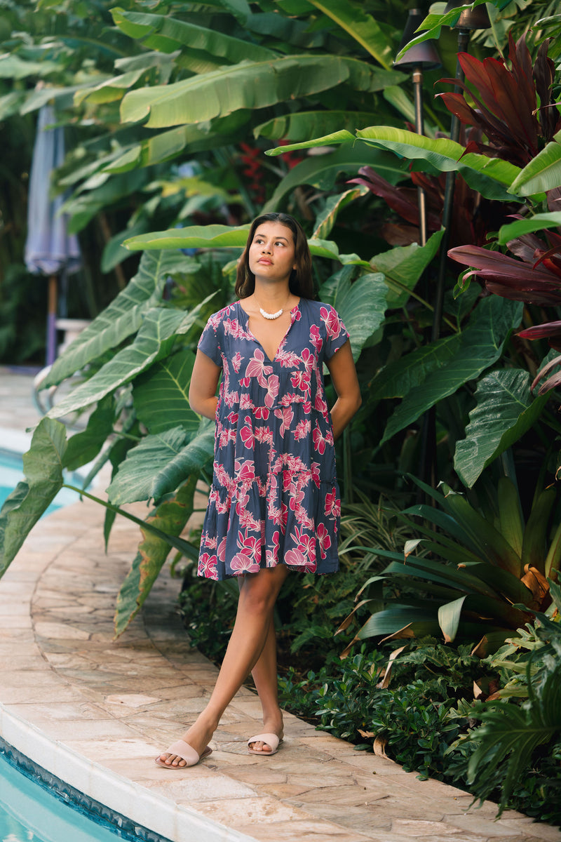 Woman wearing dress in navy with pink ginger and lei print.