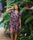 Woman wearing dress in navy with pink ginger and lei print.